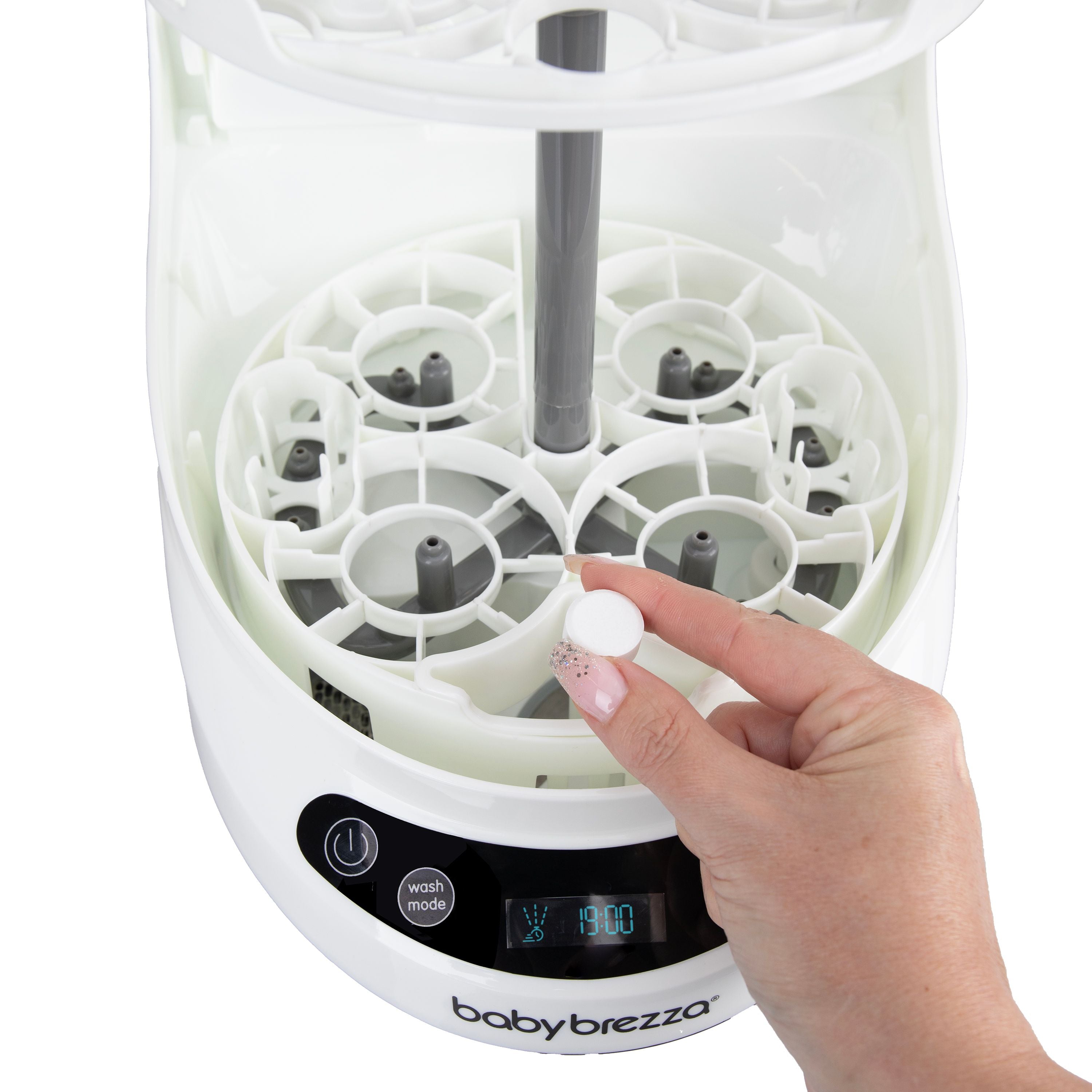A hand places a Baby Brezza Bottle Washer Pro Descaling Tablet by Baby Brezza UK inside the open washer, revealing its compartments and digital display—ideal for easy limescale removal and efficient cleaning. - product thumbnail