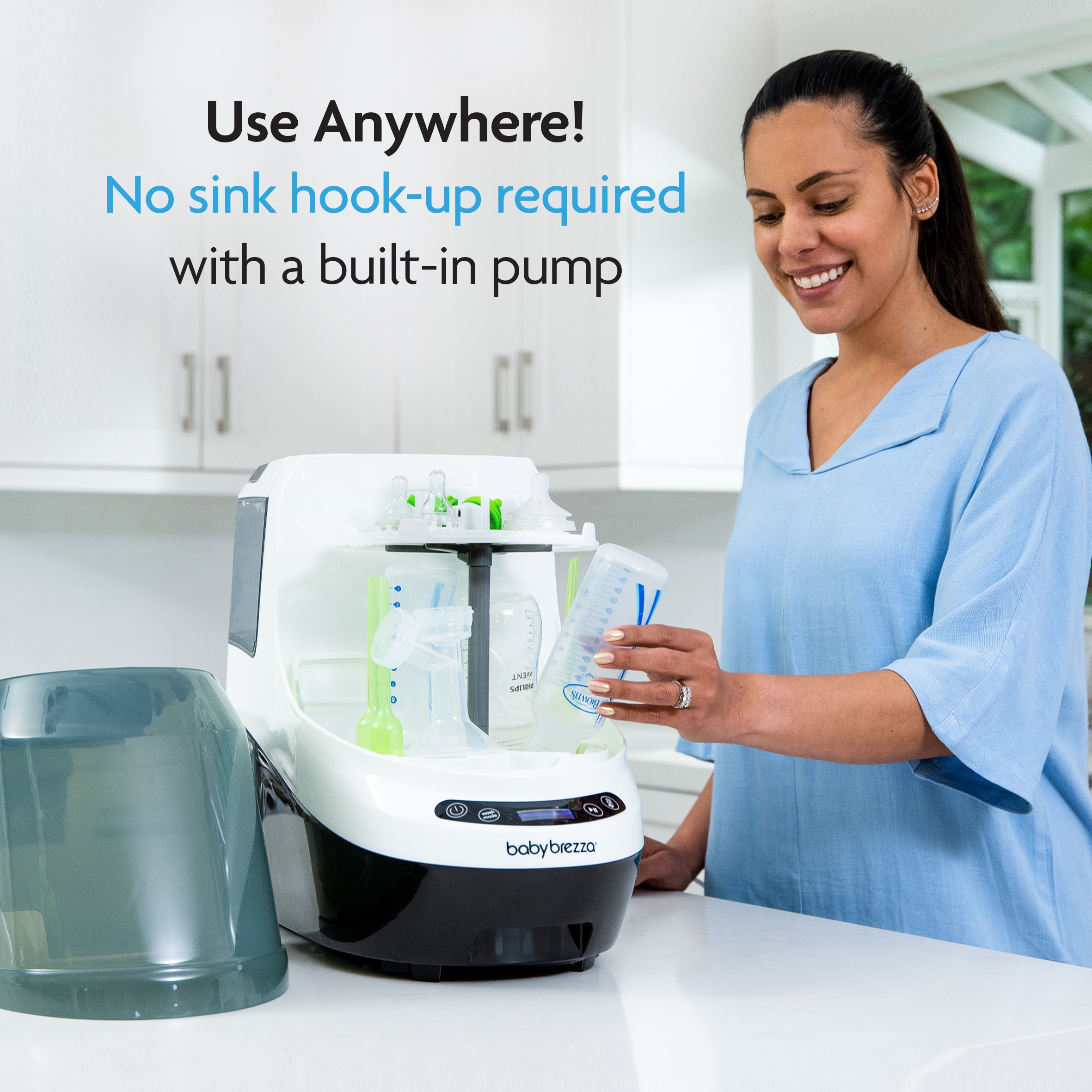 A woman smiles in a modern kitchen as she places a baby bottle in the Baby Brezza UK ULTIMATE BUNDLE: Formula Pro Advanced, Bottle Washer Pro + Accessories – All Black. Text: Use Anywhere! No sink hook-up needed thanks to the built-in pump. - product thumbnail