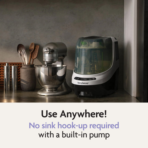 The Baby Brezza UK Bottle Washer Pro – All In One Washer, Steriliser, Dryer sits beside a mixer and utensils. Use anywhere! Its built-in pump means no sink hook-up needed—ideal for washing and sterilising baby bottles. - product thumbnail