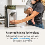 While holding a baby, a person uses the Baby Brezza UK Formula Pro Advanced, which features patented mixing technology to prepare consistently smooth formula without air bubbles. - product thumbnail