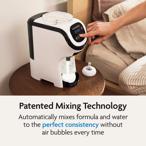 A user presses a button on the Baby Brezza UK BUNDLE Formula Pro Mini White preparing formula on a wooden table. Text below highlights its patented mixing tech for smooth, air bubble-free formula and features the SuperQuick Steriliser Black. - product thumbnail
