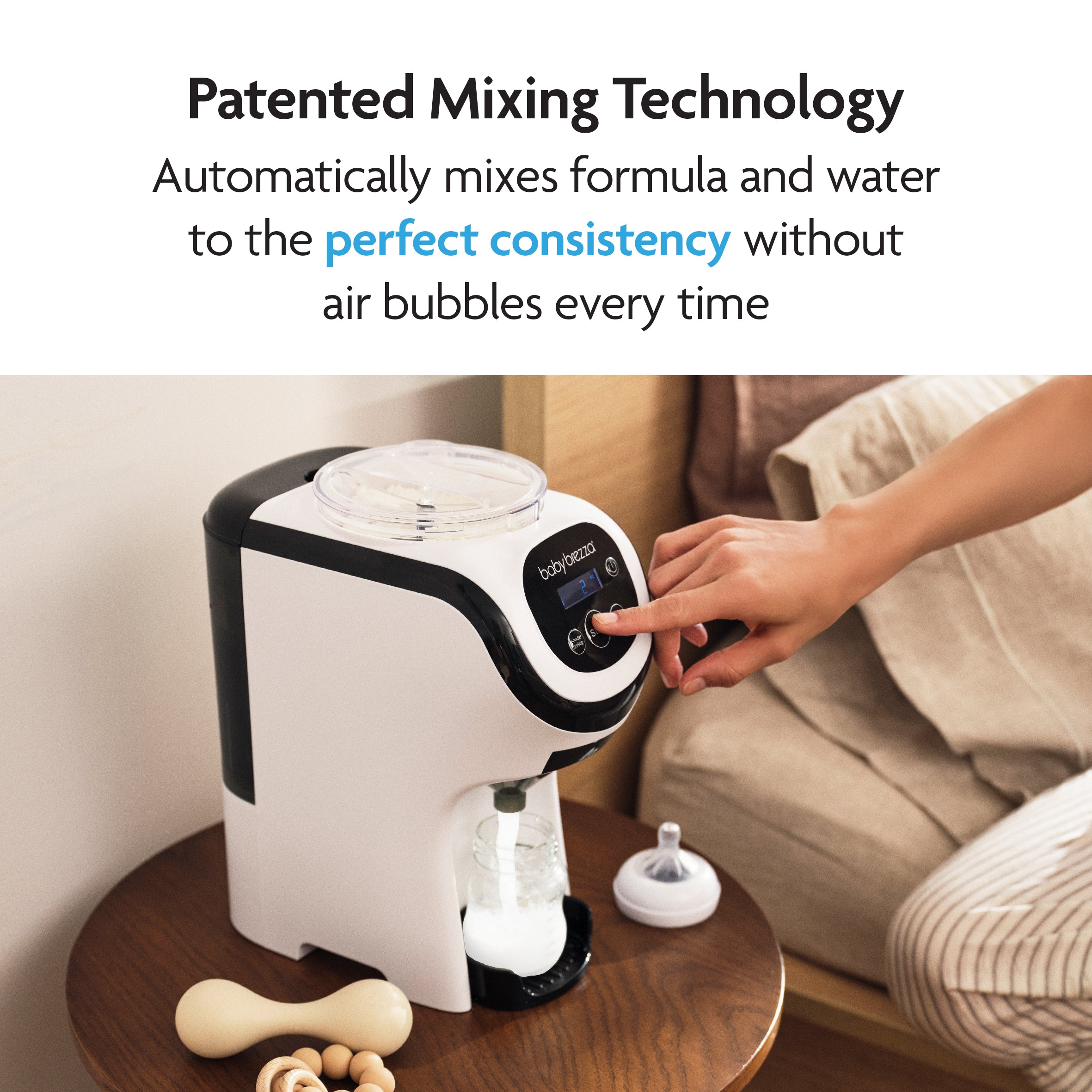 A person presses a button on the compact Baby Brezza UK Formula Pro Mini, placed on a bedside table with a bottle ready under the dispenser and a pacifier nearby. Text highlights its patented mixing technology. - product thumbnail