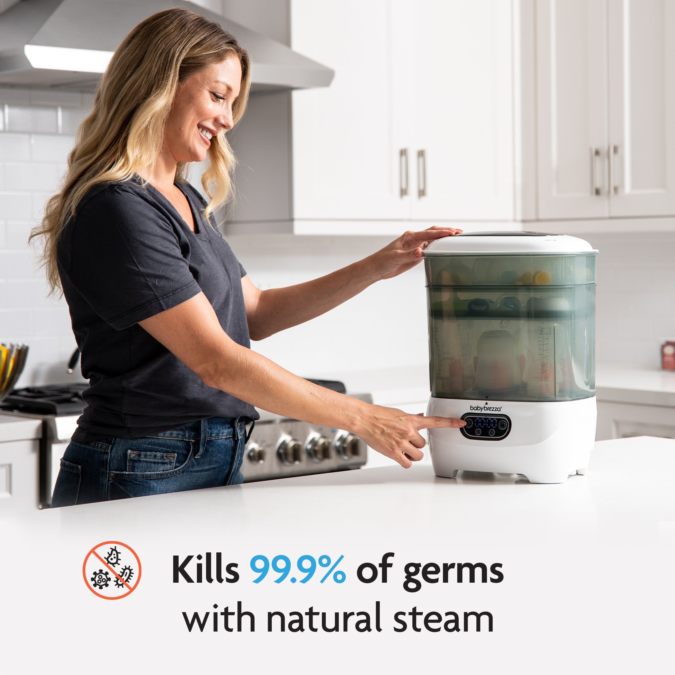 A smiling woman in a bright kitchen uses the Baby Brezza UK BUNDLE: Steriliser Dryer Advanced + Hepa Filter (White and Black). On-screen text reads: Kills 99.9% of germs with natural steam. - product thumbnail