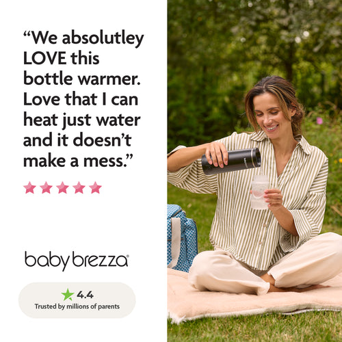 A woman smiles outdoors on a blanket, pouring hot water from the Baby Brezza UK SuperFast Portable Bottle Warmer into a baby bottle. Next to her sits a blue diaper bag and a positive review for the bottle warmer. - product thumbnail