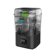 The Baby Brezza UK SuperQuick Steriliser Dryer, shown in black and transparent with a digital display, features two racks holding baby bottles, pacifiers, and bottle parts.