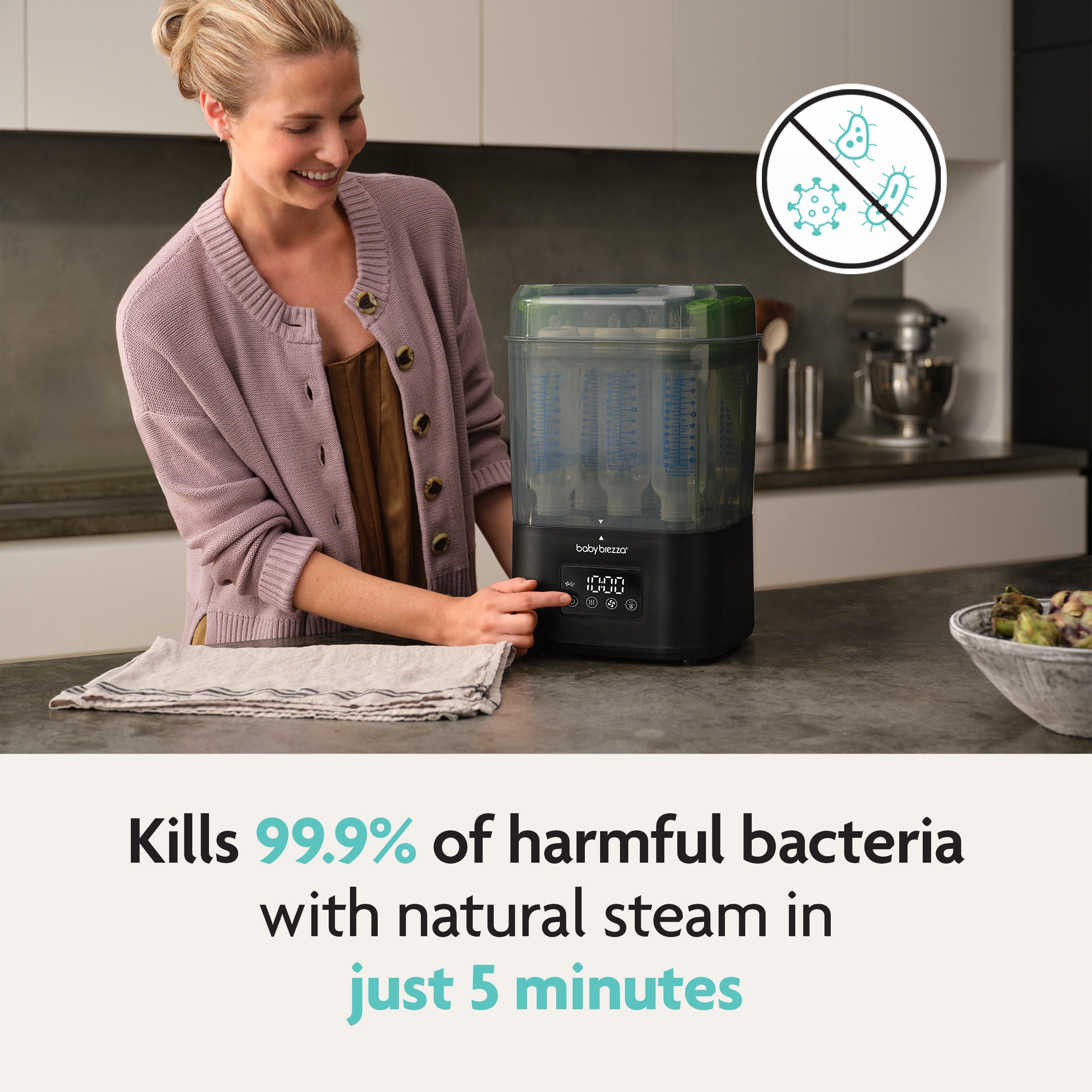 A woman smiles while using the Baby Brezza UK SuperQuick Steriliser Dryer in her kitchen. Text reads: Kills 99.9% of harmful bacteria with natural steam in 5 minutes. An icon shows bacteria crossed out. - product thumbnail