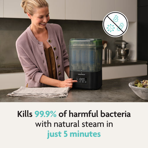 A smiling woman stands in a kitchen using the Baby Brezza SuperQuick Steriliser-Dryer. Text: Kills 99.9% of harmful bacteria with natural steam in just 5 minutes. Includes icon of bacteria crossed out. Brand: Baby Brezza UK. - product thumbnail