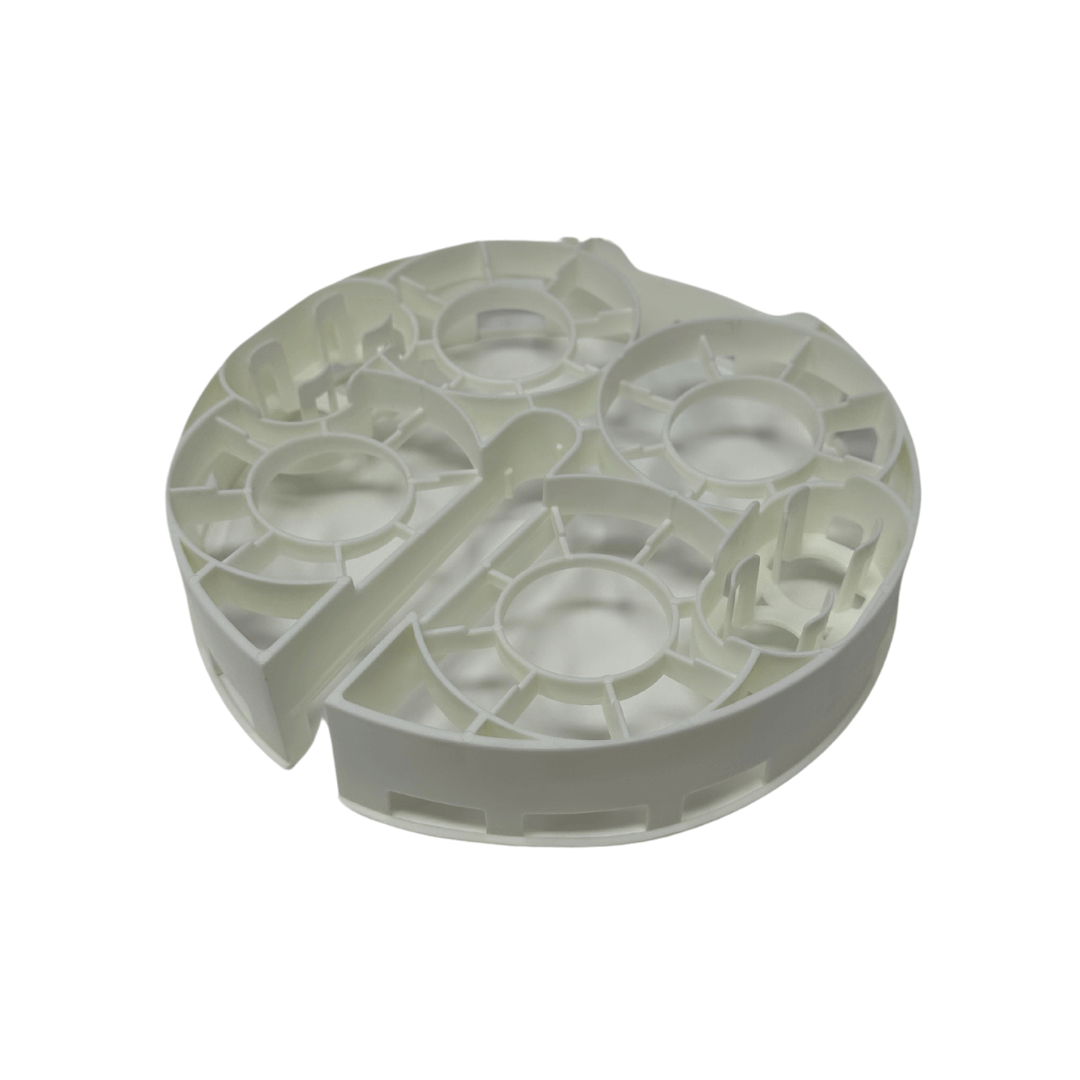 A white, circular plastic Bottle Washer Replacement Bottle Rack by Baby Brezza UK with multiple compartments and raised sections is displayed on a plain white background. - product thumbnail