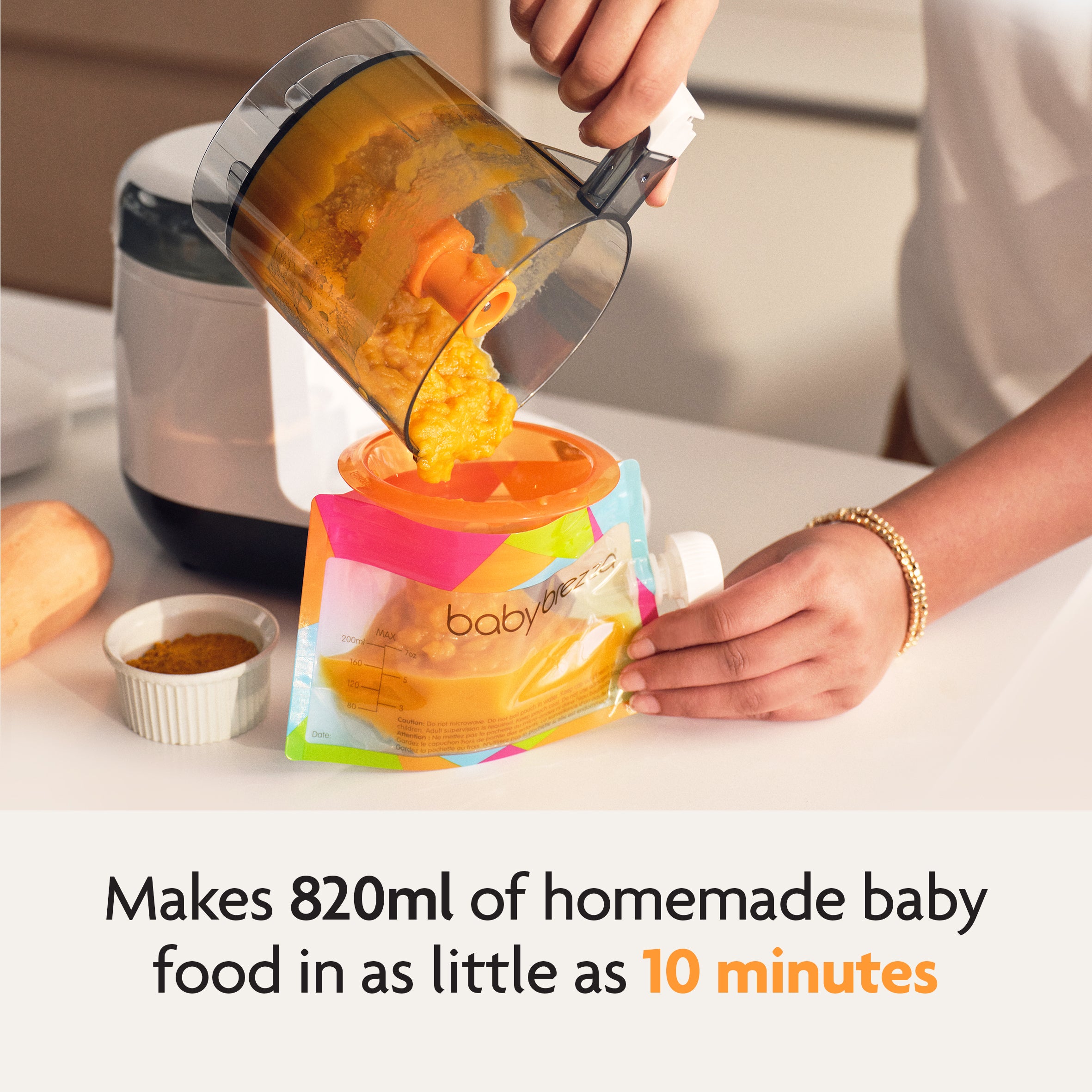 A parent pours pureed baby food from the Baby Brezza UK One Step Food Maker Deluxe into a vibrant reusable pouch. Text reads: Prepares up to 820ml of homemade baby food in just 10 minutes. - product thumbnail