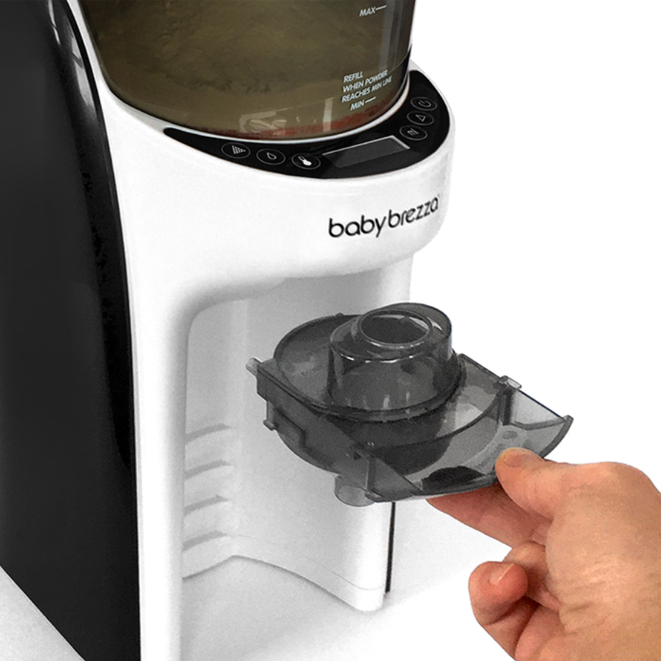 A hand removes a clear Funnel and Cover for the Formula Pro Advanced by Baby Brezza UK from the appliance, which features a digital control panel and a formula container marked with measurement levels. - product thumbnail